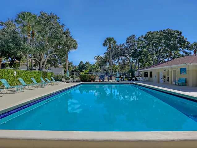 a view of swimming pool with seating space and trees in the background
