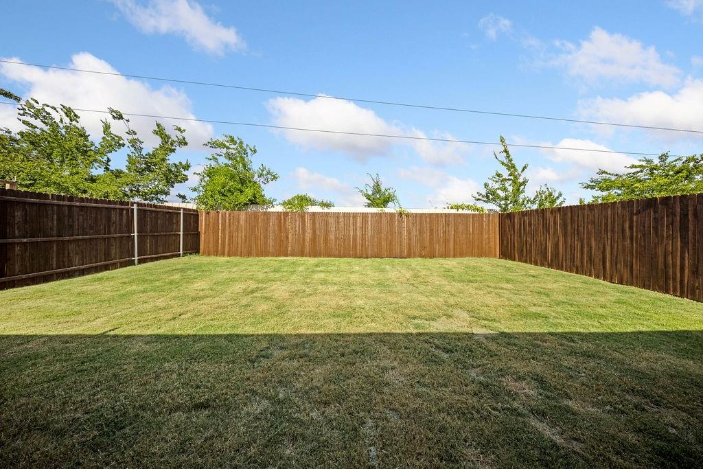822 Ramble Road Lavon, TX 75166 - Photo 35 of 35 Expansive backyard featuring a manicured lawn, full wood fencing, and mature perimeter trees
