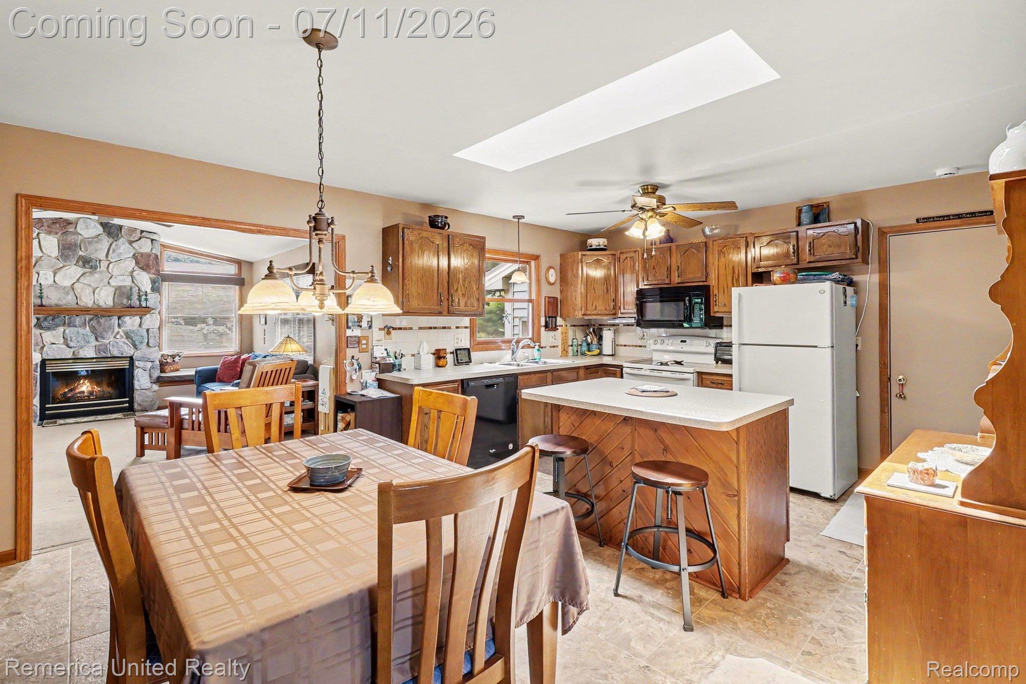 136 Endicott Howell, MI 48843 - Photo 10 of 28 Bright kitchen and dining area featuring wood-finish cabinetry, an island with countertop seating, and recessed lighting