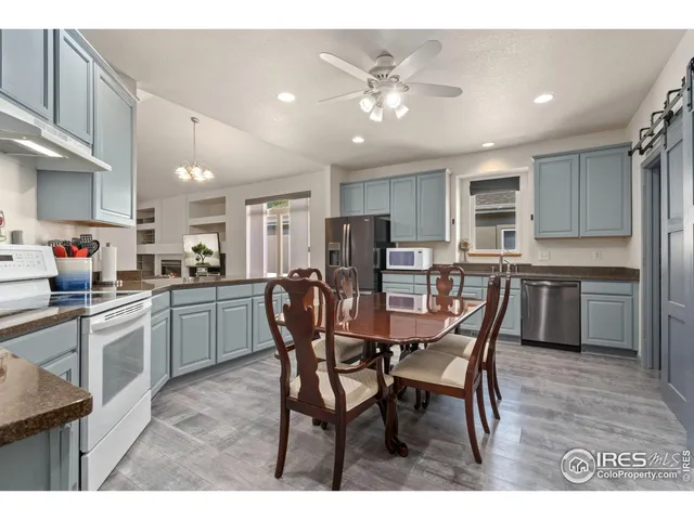 a open dining room with stainless steel appliances kitchen island granite countertop a dining table chairs and a refrigerator