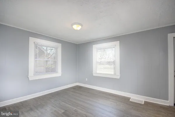 an empty room with wooden closet and windows