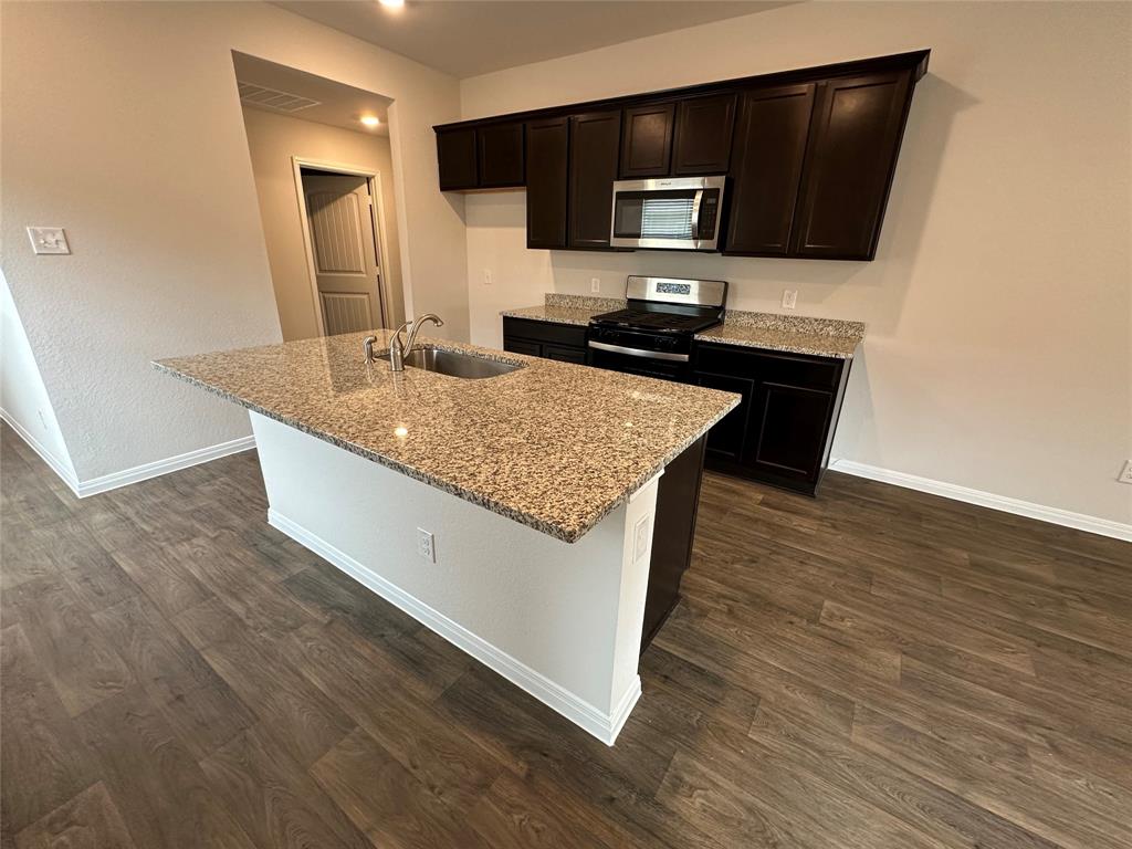 563 Evergreen Sumac Loop Kyle, TX 78640 - Photo 6 of 18 A contemporary kitchen features dark cabinetry, granite countertops, and sleek stainless steel appliances.