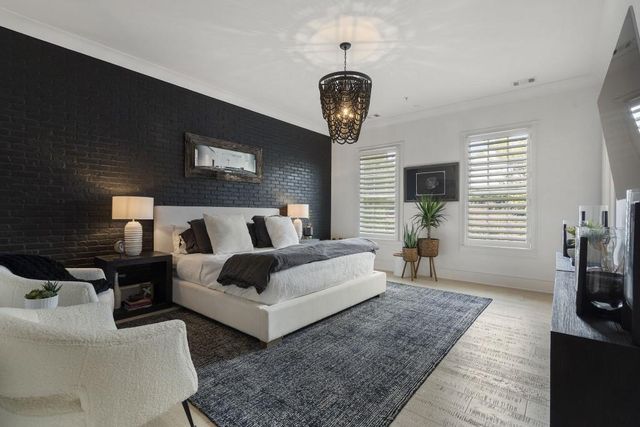 a spacious bedroom with bed and a flat tv screen