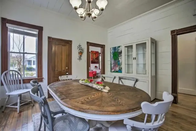 a kitchen with stainless steel appliances granite countertop a stove a refrigerator a sink a dining table and chairs with wooden floor