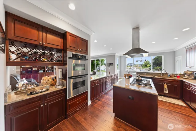 a kitchen with stainless steel appliances kitchen island granite countertop a stove refrigerator and a sink