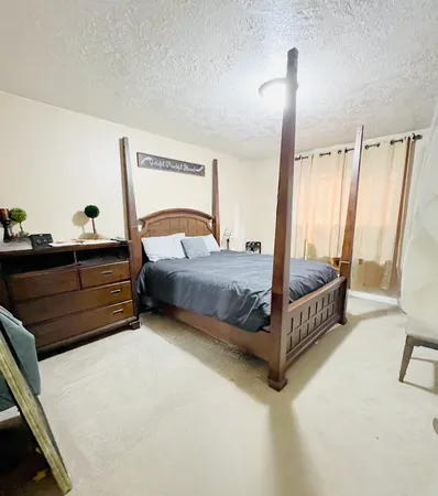 a bedroom with a bed lamp and a large window