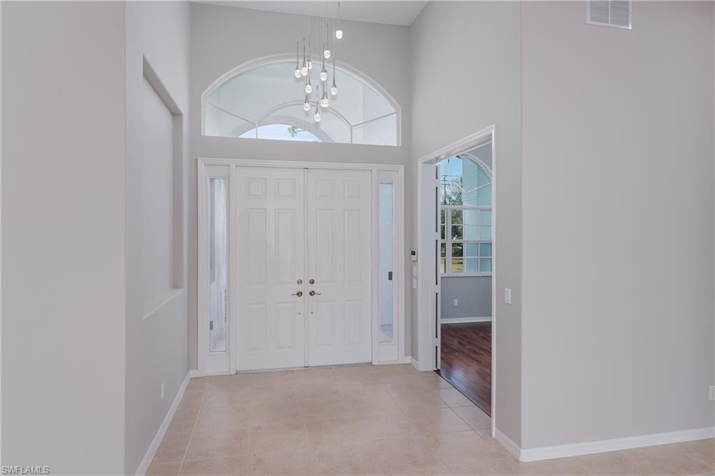510 13th Street Northwest Naples, FL 34120 - Photo 13 of 50 an empty room with wooden floor chandelier and hallway