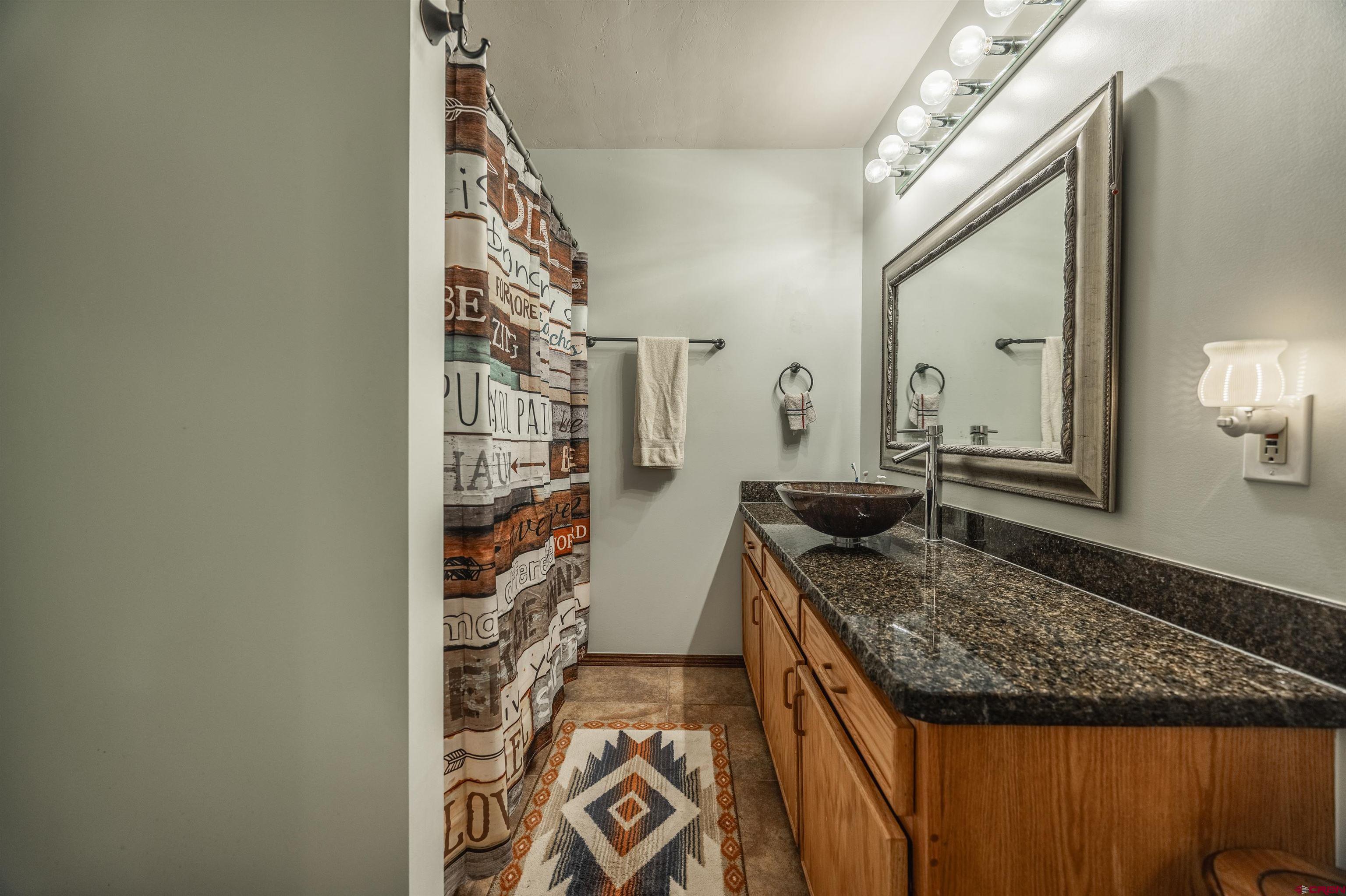21186 Uintah Road Cedaredge, CO 81413 - Photo 19 of 45 a bathroom with a granite countertop sink and a mirror