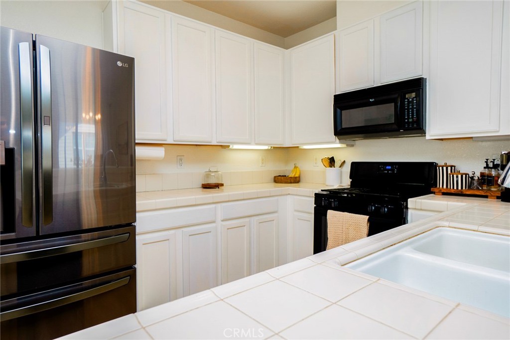 7331 Shelby Place, Unit 91 Rancho Cucamonga, CA 91739 - Photo 14 of 34 a kitchen with stainless steel appliances a refrigerator sink and white cabinets