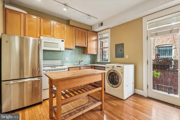 a view of a kitchen with fridge and wooden floor