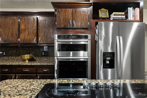 a kitchen with granite countertop a refrigerator stove and oven