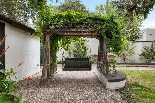 a view of patio with table and chairs under an umbrella with large trees