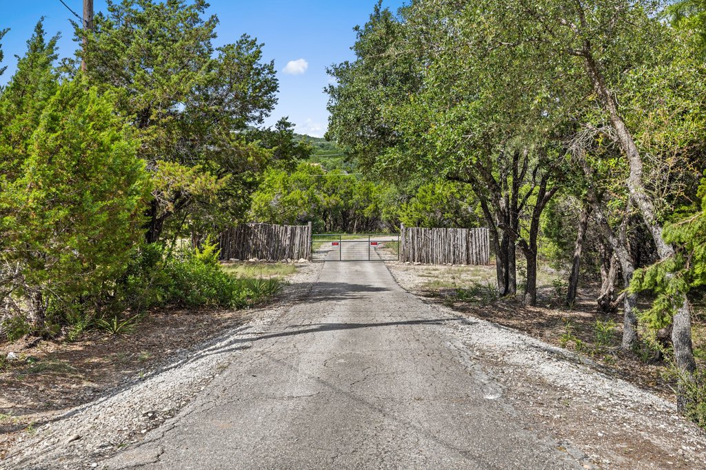 23644 Nameless Road Leander, TX 78641 - Photo 40 of 40 A private, tree-lined driveway leads to a secure gated entrance, offering secluded acreage with natural landscaping.
