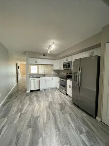a view of a kitchen with wooden floor and electronic appliances