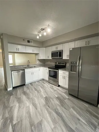 a kitchen with stainless steel appliances granite countertop a refrigerator a stove top oven a sink and dishwasher