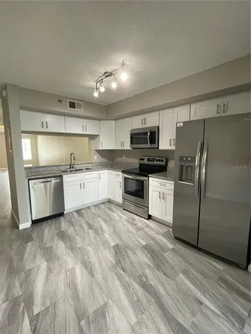 a kitchen with stainless steel appliances granite countertop a refrigerator a stove top oven a sink and dishwasher