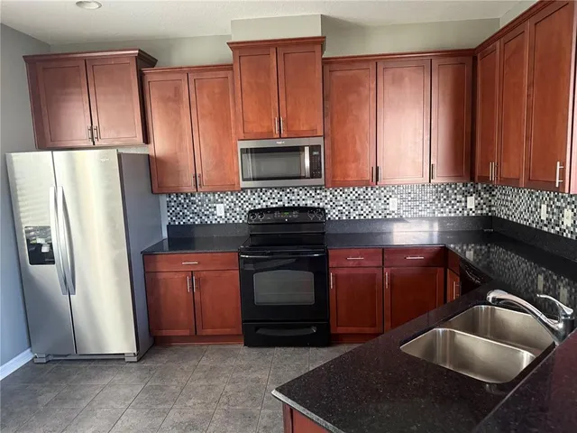 a kitchen with granite countertop a refrigerator stove and sink