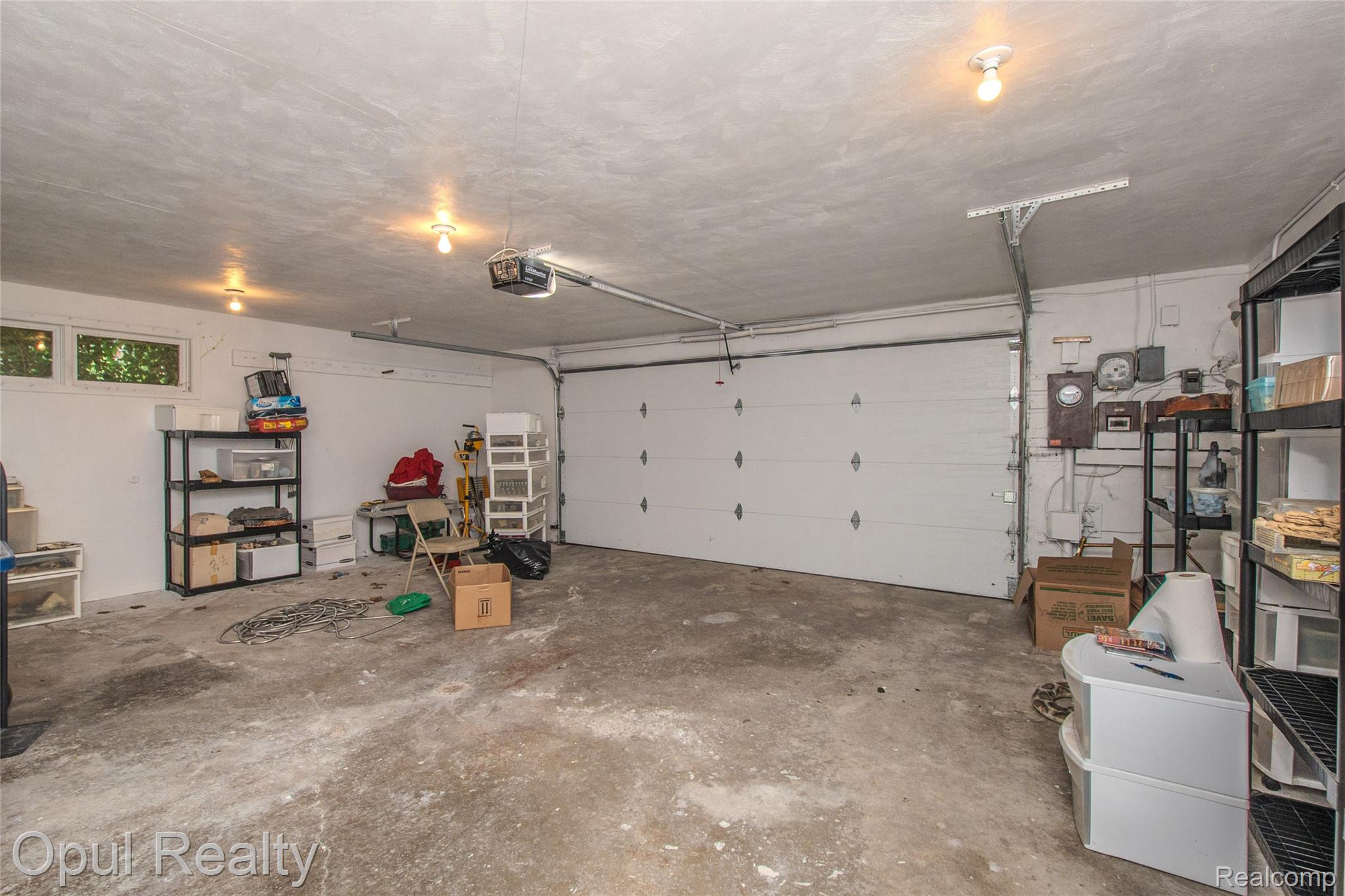 6455 Norham Road Bloomfield Hills, MI 48301 - Photo 58 of 93 Attached garage space featuring a paneled garage door, exposed concrete flooring, and multiple ceiling-mounted light fixtures