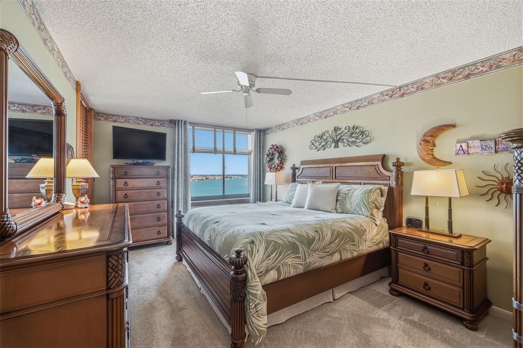 9425 Blind Pass Road, Unit 705 St. Pete Beach, FL 33706 - Photo 21 of 66 a bedroom with a bed and a flat tv screen on dresser