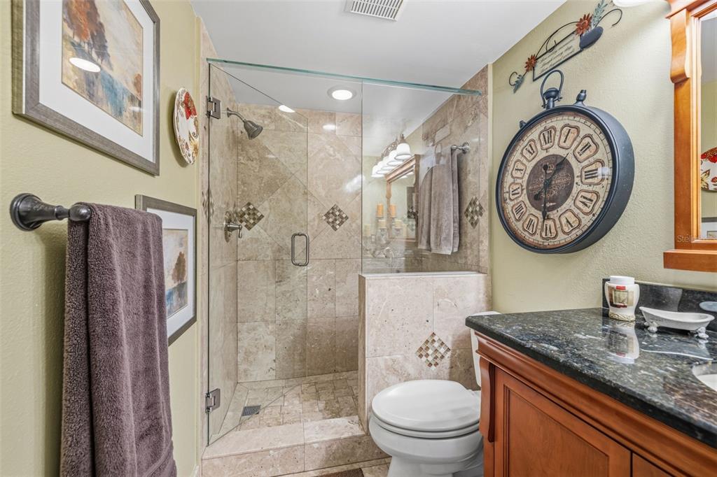 9425 Blind Pass Road, Unit 705 St. Pete Beach, FL 33706 - Photo 24 of 66 a bathroom with a granite countertop toilet a sink and a shower