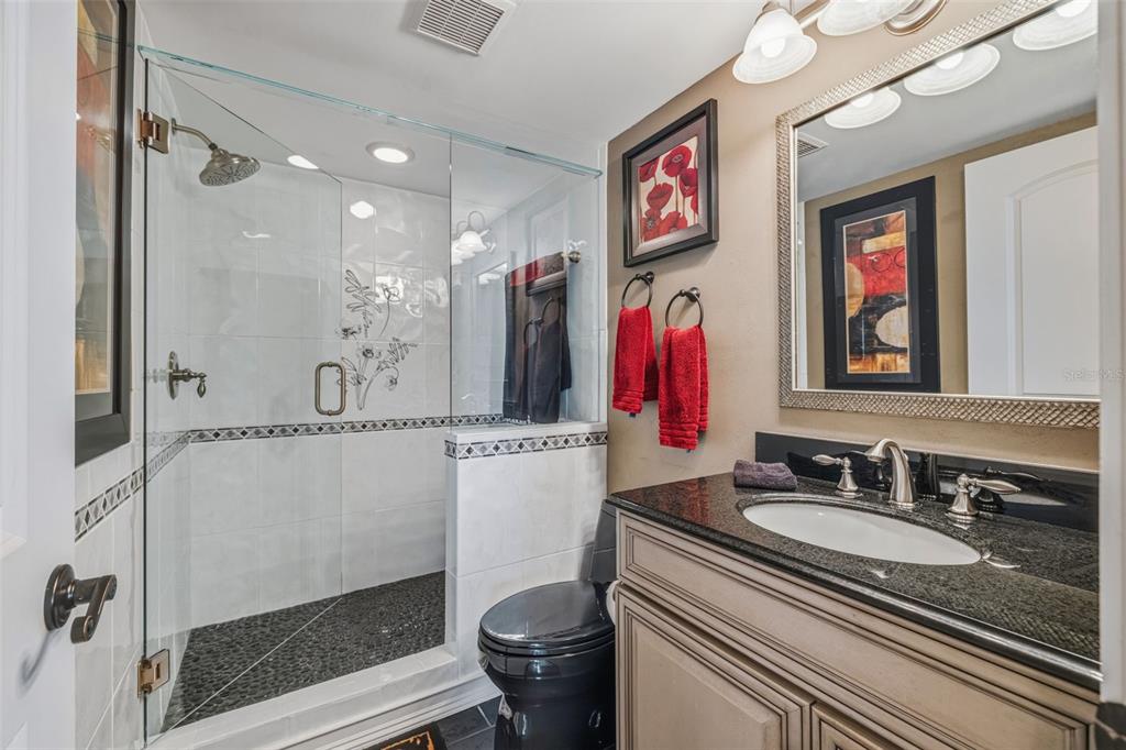 9425 Blind Pass Road, Unit 705 St. Pete Beach, FL 33706 - Photo 32 of 66 a bathroom with a granite countertop sink mirror vanity and toilet