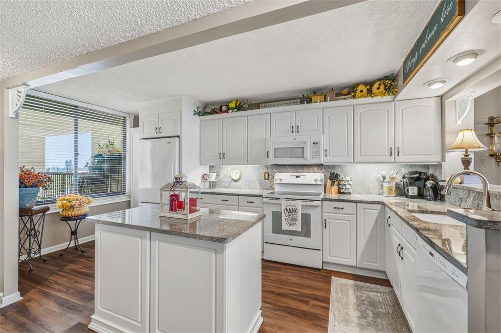 9425 Blind Pass Road, Unit 705 St. Pete Beach, FL 33706 - Photo 5 of 66 a kitchen with a sink cabinets and wooden floor