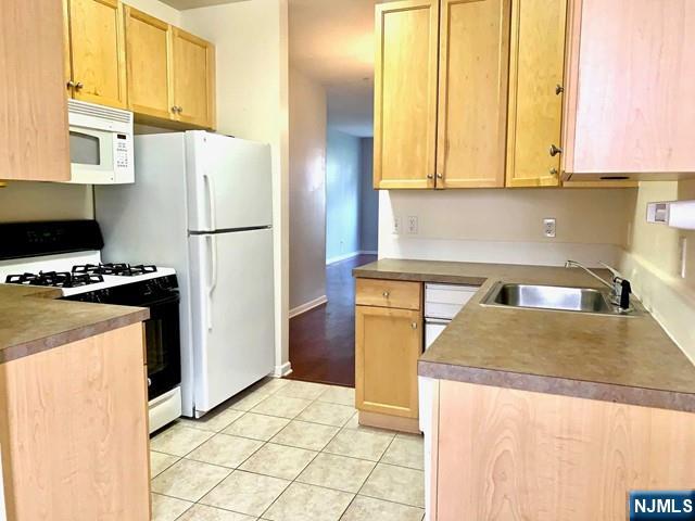 201 Dey Street, Unit 162 Harrison, NJ 07029 - Photo 4 of 21 a kitchen with stainless steel appliances granite countertop a refrigerator a stove and a sink with wooden cabinets