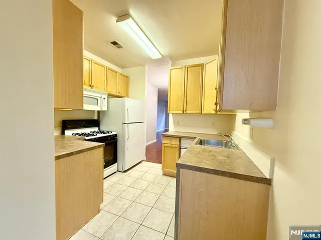 a kitchen with a refrigerator a stove a sink dishwasher and wooden cabinets
