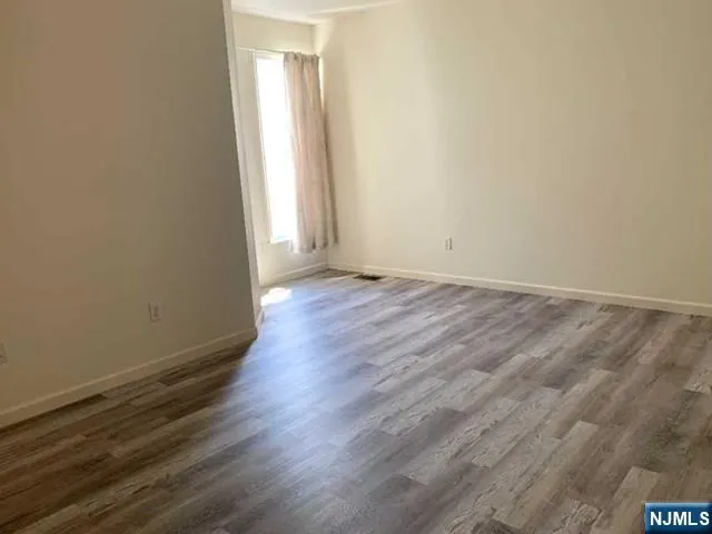 an empty room with wooden floor and window