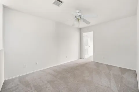 an empty room with a window and chandelier fan