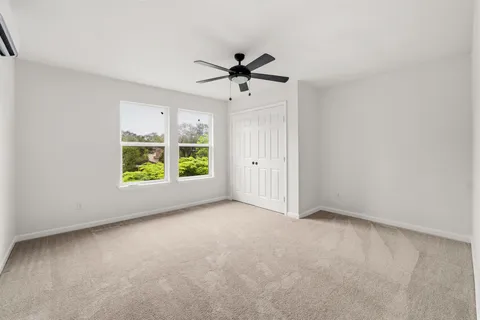 an empty room with windows and ceiling fan