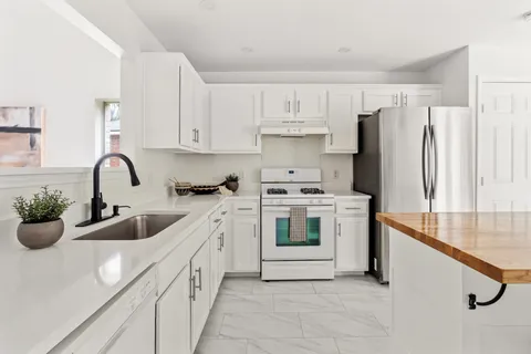 a kitchen with white cabinets and sink