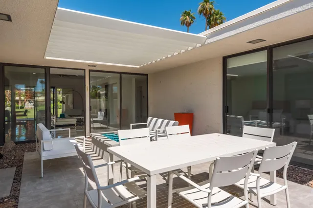 a patio with table and chairs and potted plants