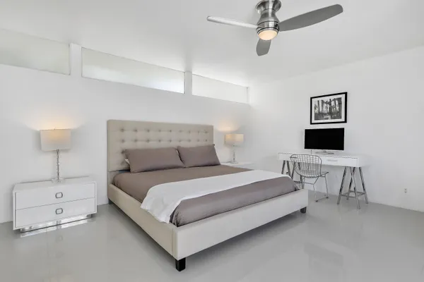 a bedroom with a bed tv and a large window