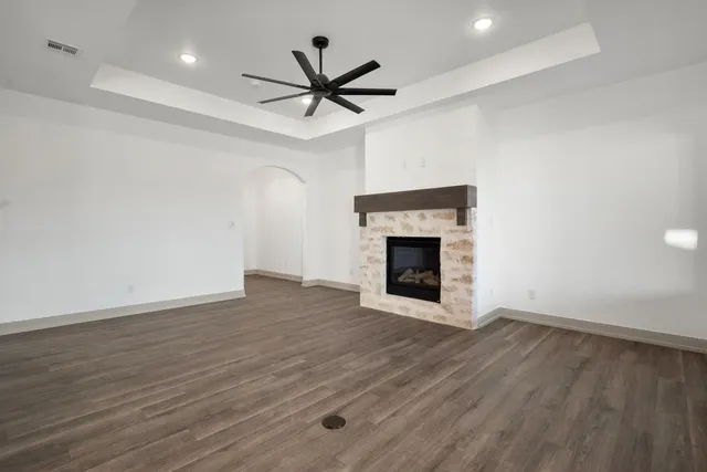 an empty room with wooden floor a ceiling fan a fireplace and a ceiling fan