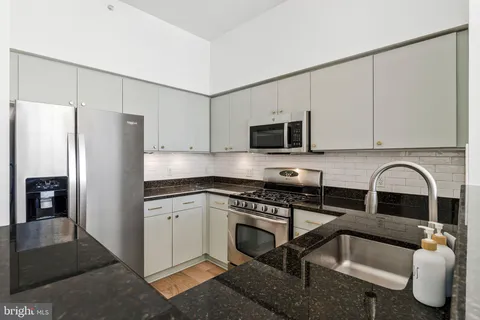 a kitchen with stainless steel appliances granite countertop a refrigerator sink and stove