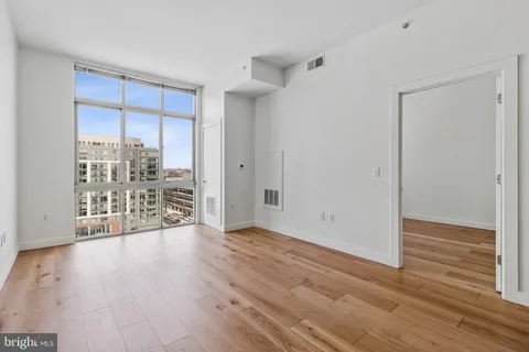 a view of an empty room with wooden floor and a window