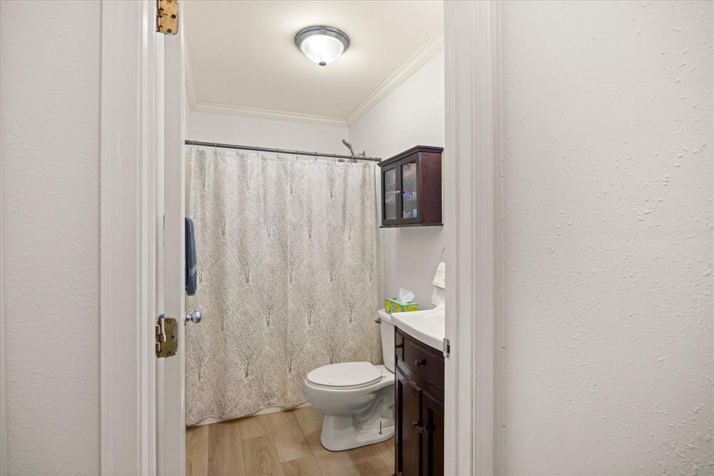 310 West 6th Street Tolar, TX 76476 - Photo 11 of 27 a white toilet sitting next to a shower curtain