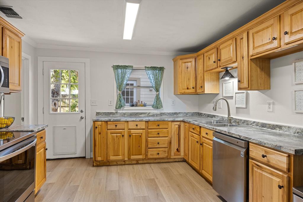 310 West 6th Street Tolar, TX 76476 - Photo 6 of 27 a kitchen with stainless steel appliances granite countertop wooden cabinets a stove a sink and a window