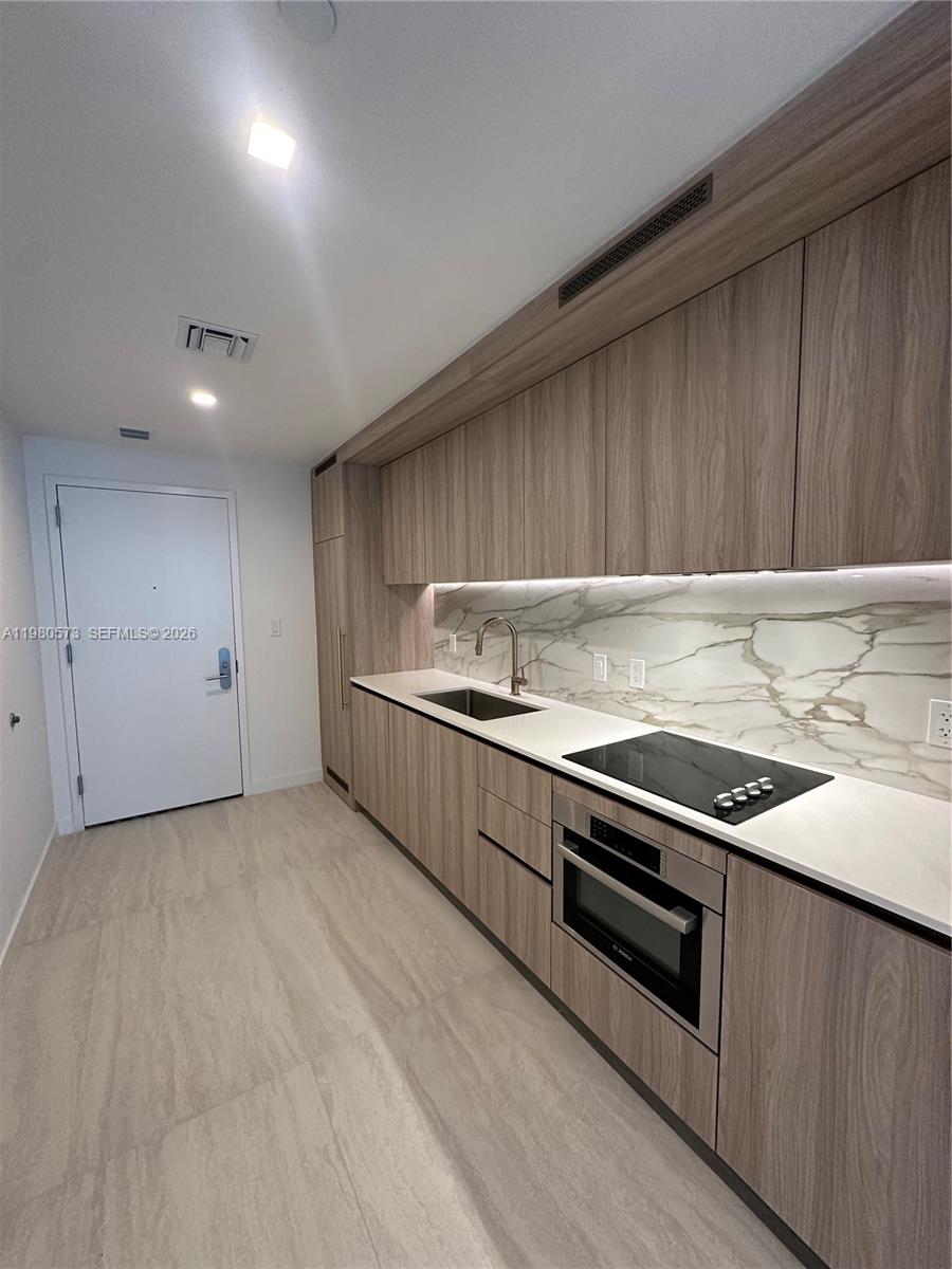 77 Southeast 5th Street, Unit 1514 Miami, FL 33131 - Photo 3 of 16 a kitchen with granite countertop a stove and a sink