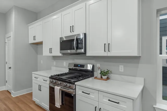 a kitchen with stainless steel appliances white cabinets and a stove top oven