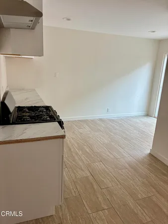 a room with wooden floor cabinetry and a stove top oven