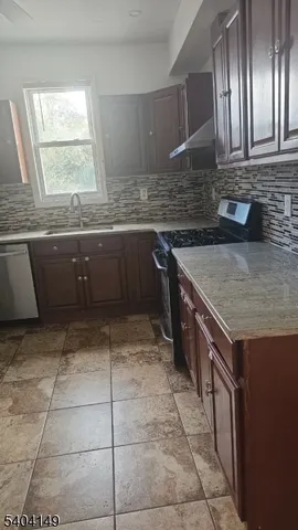 a kitchen with kitchen island granite countertop a sink a counter top space and cabinets