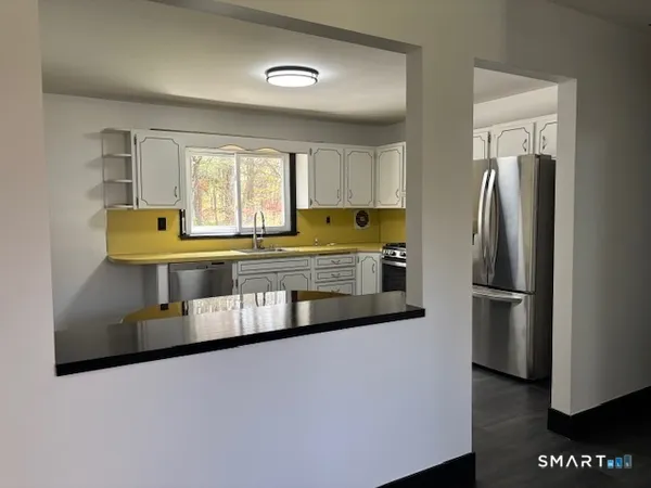 a kitchen with stainless steel appliances a refrigerator a sink a stove and white cabinets