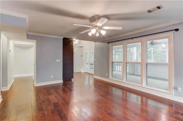 a view of an empty room with wooden floor and a window