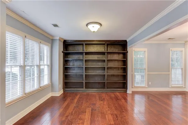 a view of an empty room with a window and wooden floor