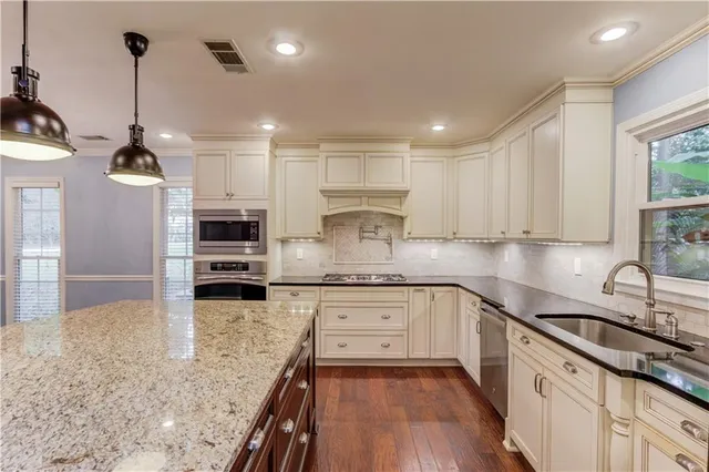 a kitchen with stainless steel appliances granite countertop a sink a stove and a wooden floors