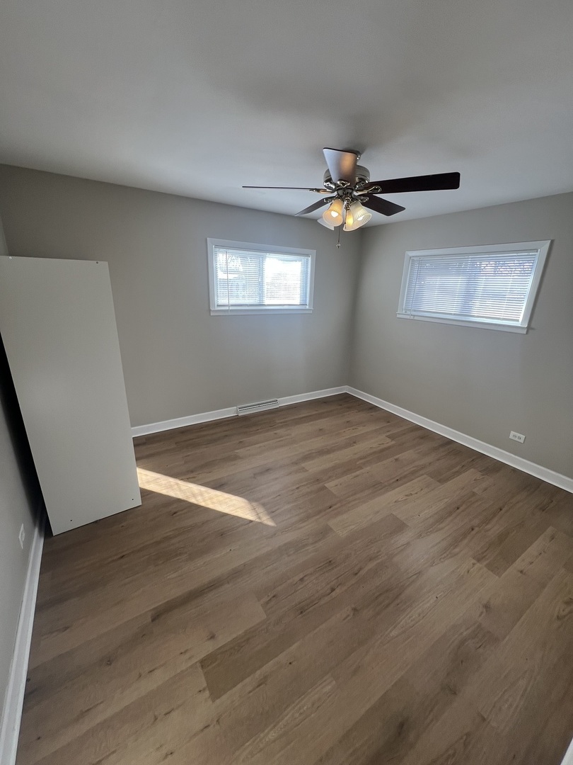 213 67th Street Darien, IL 60561 - Photo 8 of 13 an empty room with wooden floor ceiling fan and windows