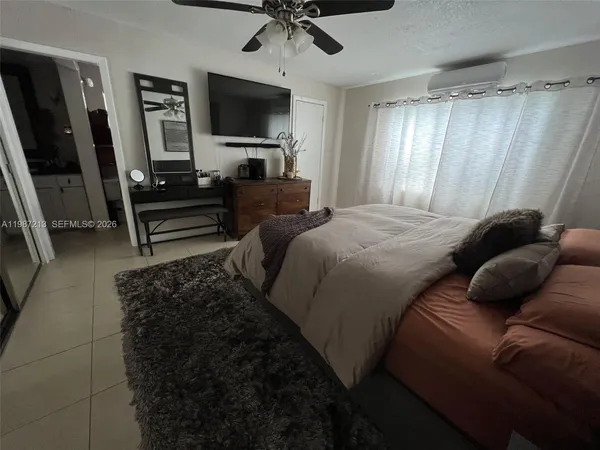 a bedroom with a bed a couch and a flat tv screen