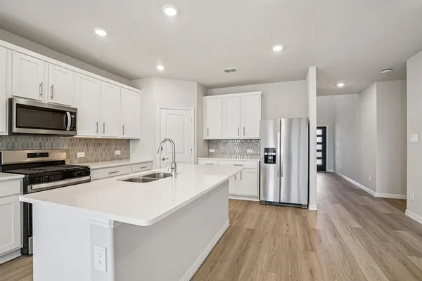 a kitchen with a refrigerator a stove top oven a sink and cabinets with wooden floor